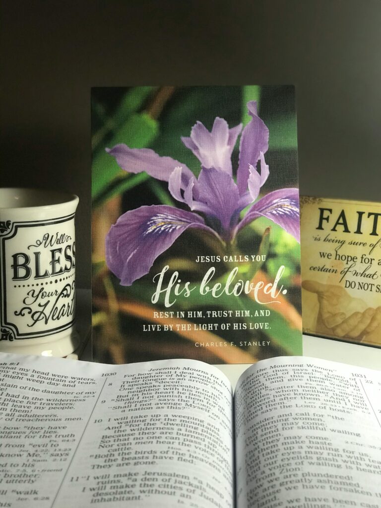 Opened textbook placed on table in room near mug and pictures with religious inscriptions