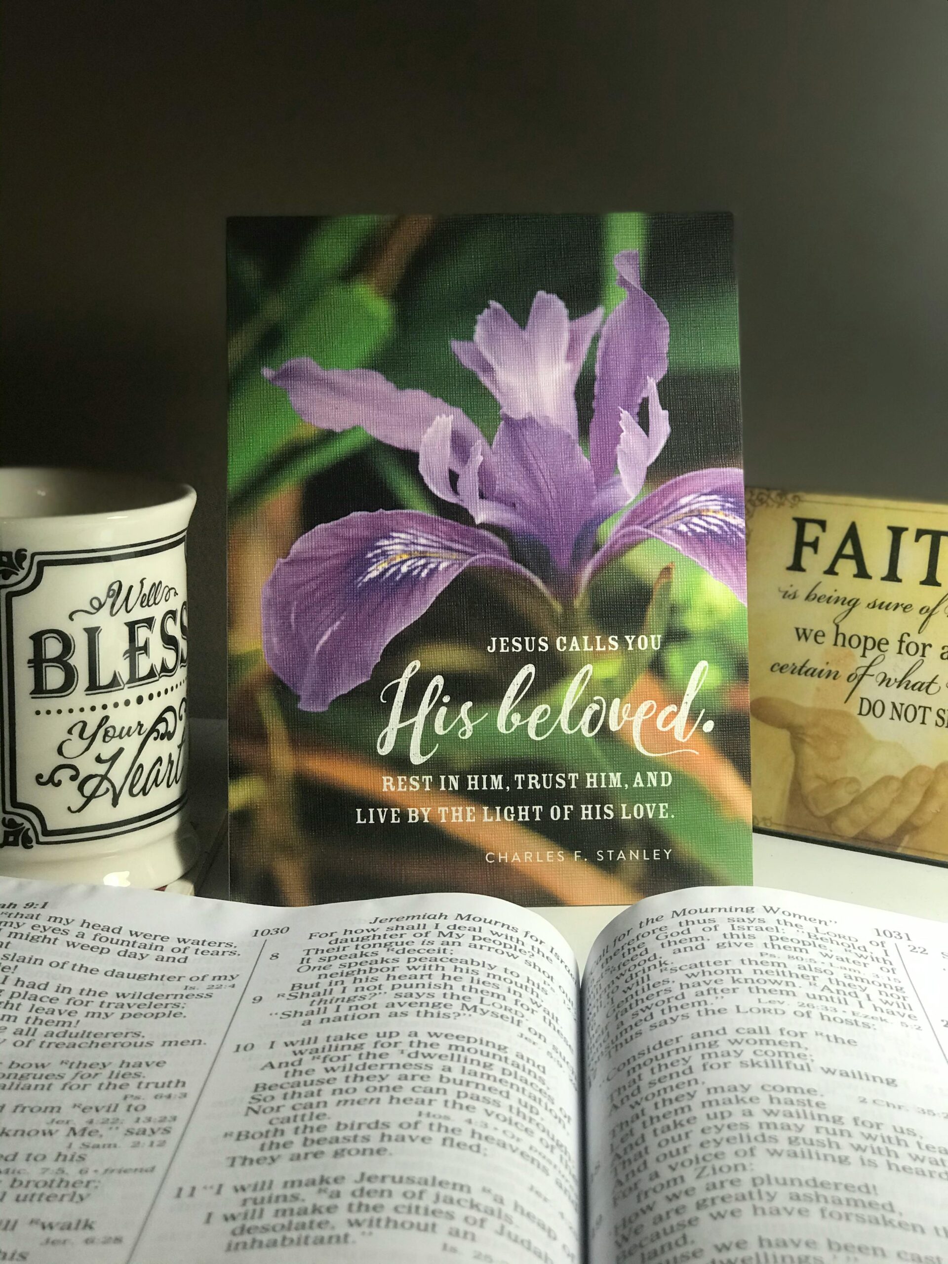 Opened textbook placed on table in room near mug and pictures with religious inscriptions