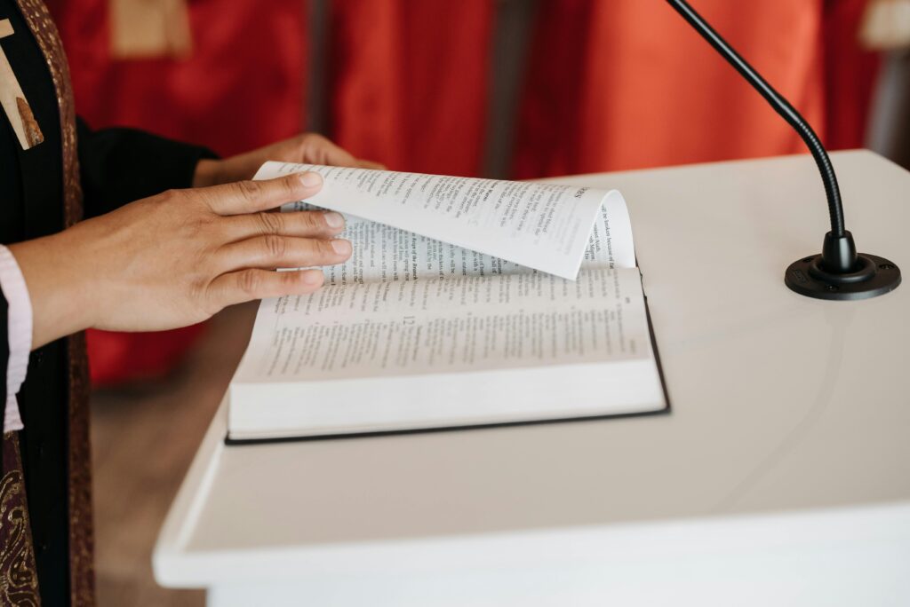 Close-up of a person reading the Bible at a church podium during a religious ceremony.